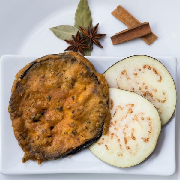 Fried eggplant slices and raw eggplant slices with star anise, bay leaves, and cinnamon sticks.
