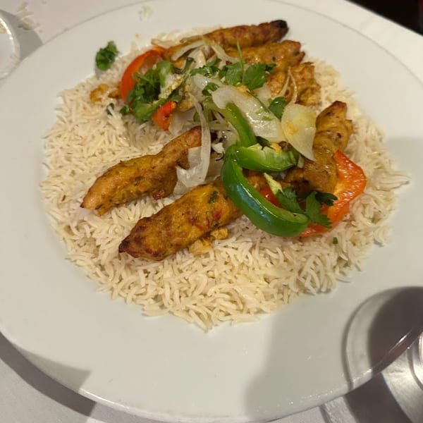 Indian chicken seekh kebab with basmati rice, bell peppers, and onions on a white plate.